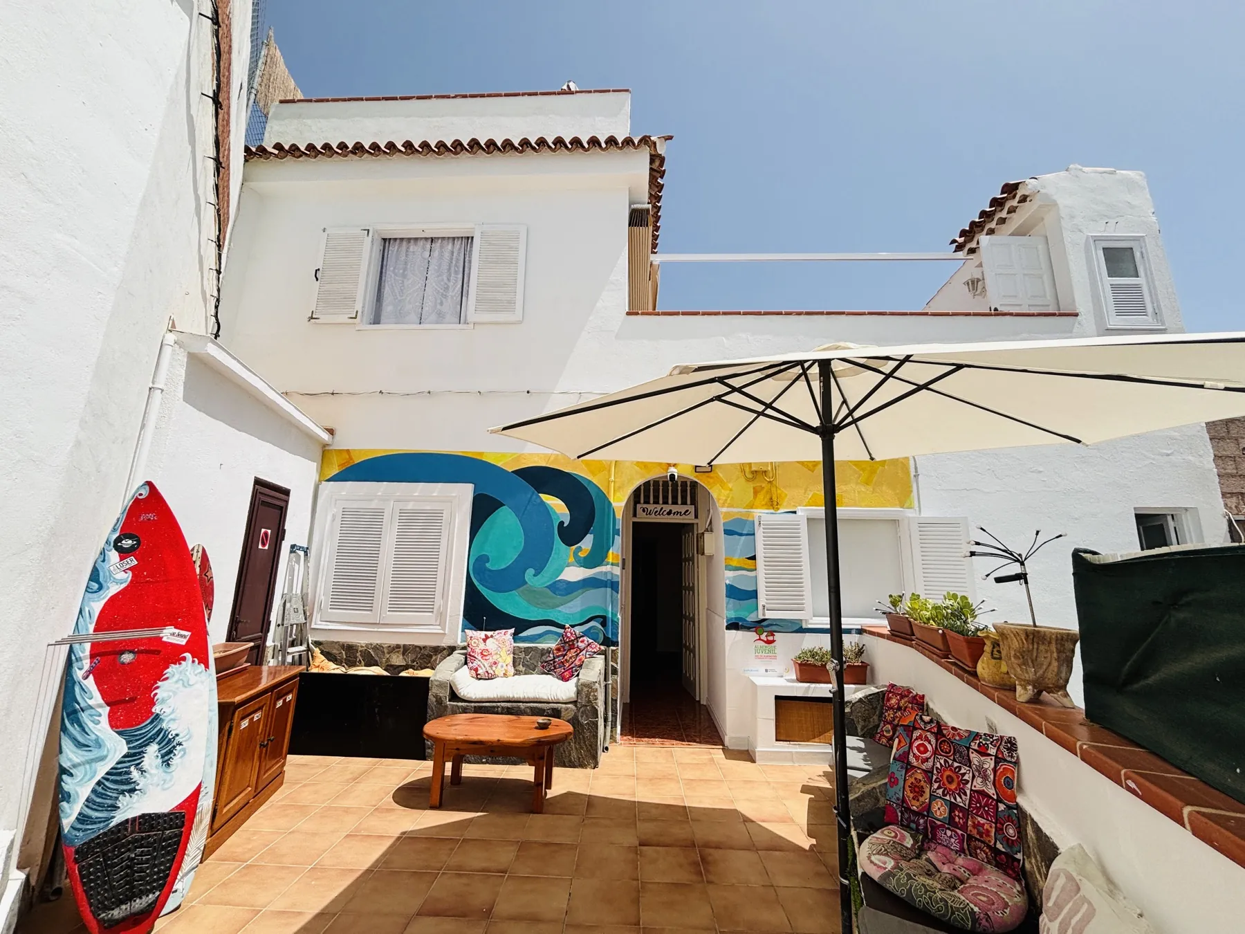 Terraza de Banana Surf House con el mural de la ola y las tablas de surf